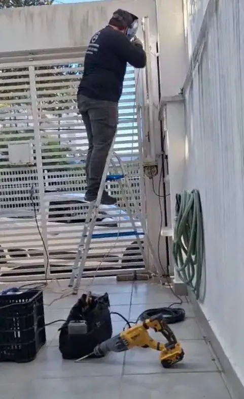 Técnico da LCA em uma escada soldando o portão de uma residência